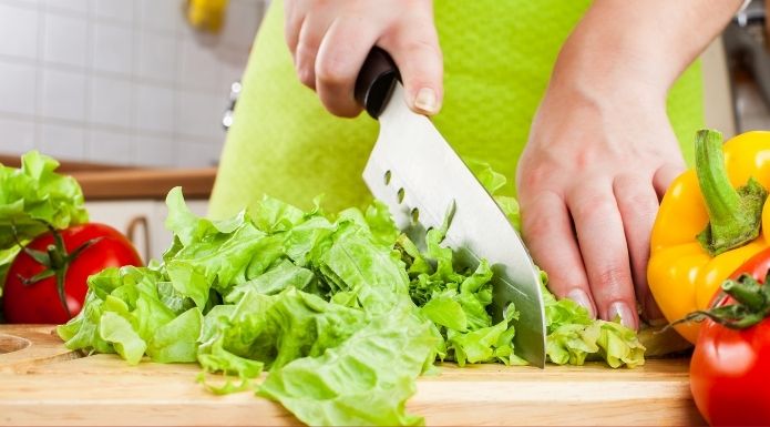Home cook cutting lettuce with a knife.