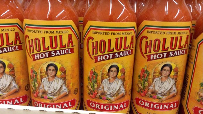 bottles of Cholula Hot Sauce on grocery store shelves, close up