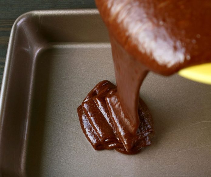 pouring chocolate cake batter into sheet pan