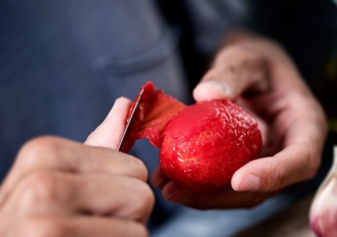person peeling a tomato