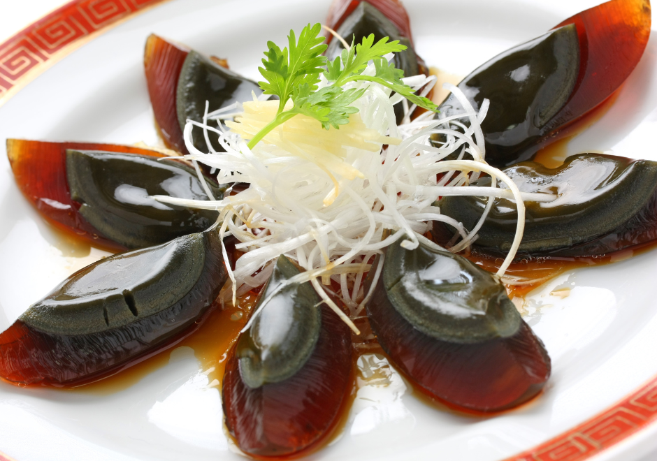 Chinese Century Eggs quartered and arranged on plate with garnish