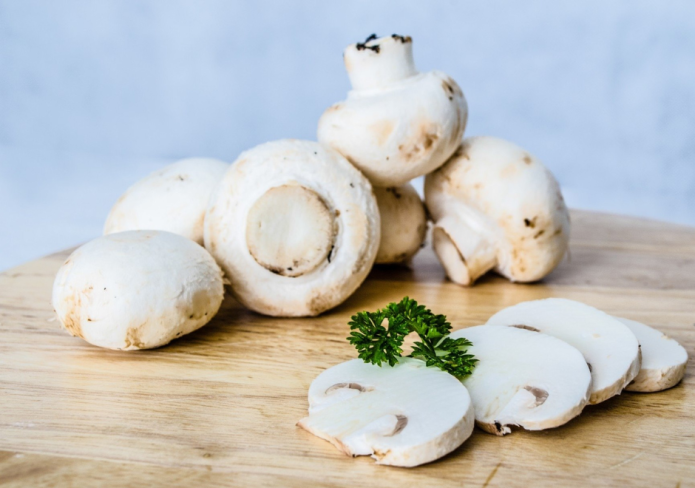 white cultivated mushrooms on cutting board
