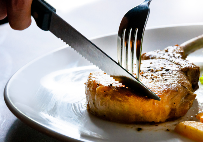 cutting into yummy pork chop for dinner