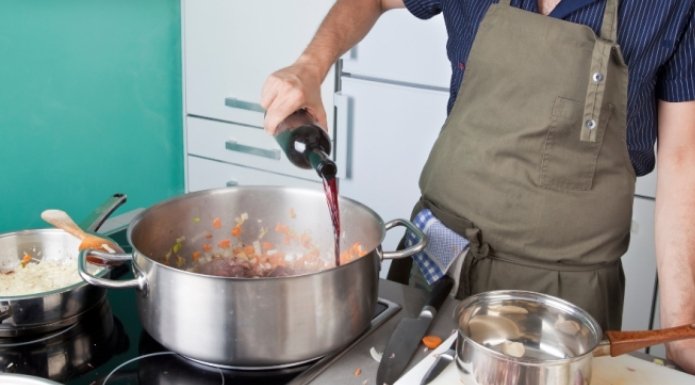 adding wine to pot of cooking food