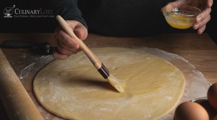 using pastry brush to apply butter to dough