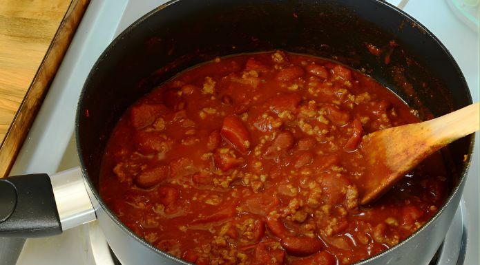 A small pot of chili on the stove, showing the process of reheating leftovers safely.