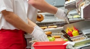 Fast food workers putting American cheese on burgers.