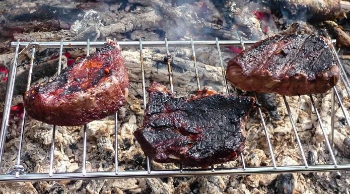Cooking steaks over campfire coals, an historical cooking method that we never lost. 